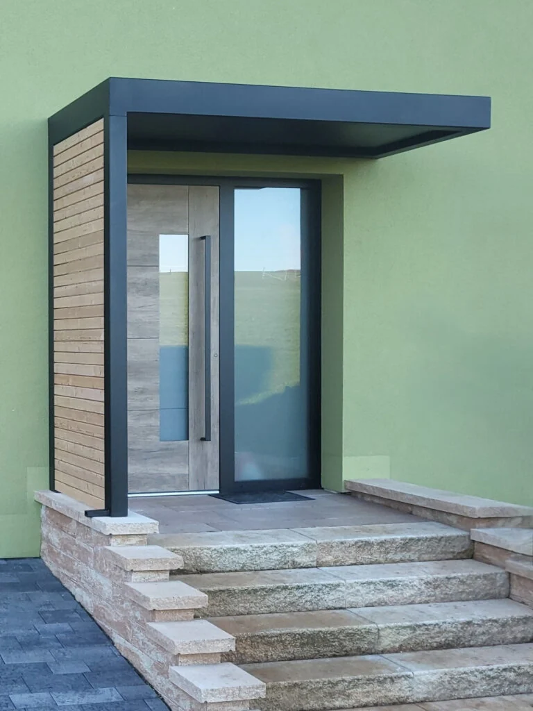 Stahlvordach mit Seitenteil und Holz-Rhombusleisten über einem Hauseingang